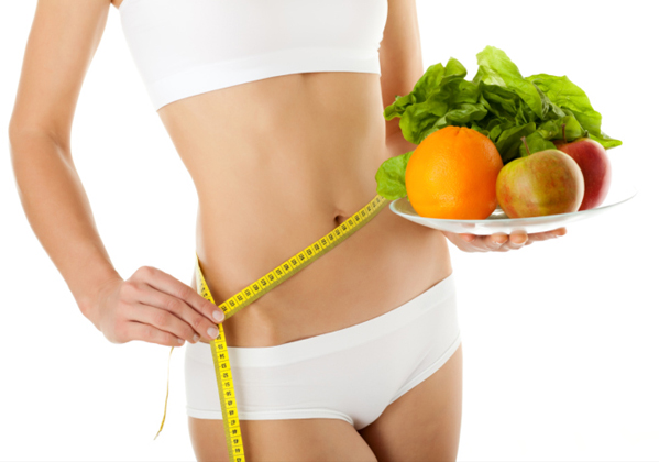 Chica con plato verduras y fruta con cinta métrica en su cintura