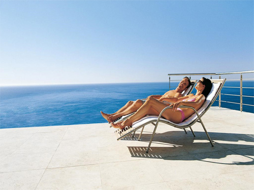 Pareja tomando el sol en terraza con el mar al fondo